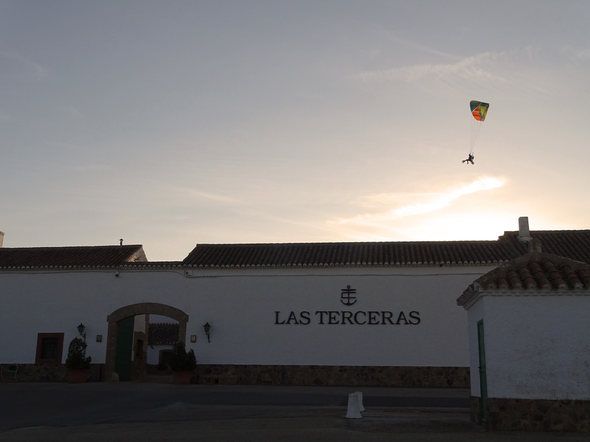 A paramotor flies above the entrance to Finca Las Terceras at sunset