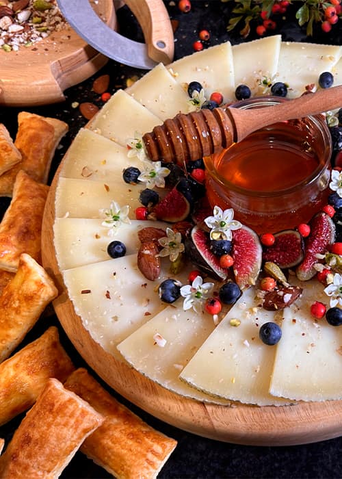 Tabla de queso manchego con miel, higos y frutos rojos