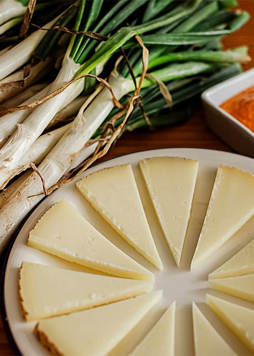 Manchego cheese with calçots and romesco sauce